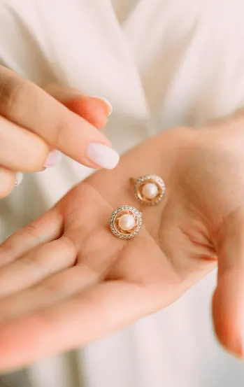 Hands holding a pair of gold earrings